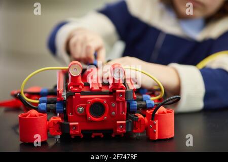 Nahaufnahme eines nicht erkennbaren Jungen Jungen, der eine rote Robotermaschine baut, während er den Ingenieurunterricht in der Entwicklungsschule genießt, Platz zum Kopieren Stockfoto