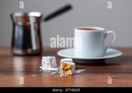 Traditioneller türkischer Kaffee in klassischen Tassen mit türkischen Köstlichkeiten. Im Hintergrund befindet sich eine Kaffeekocher aus Metall. Stockfoto