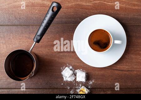 Flachlagerung von oben, Bild mit traditionellem türkischen Kaffee, serviert in klassischen Tassen mit türkischen Köstlichkeiten. Im Hintergrund befindet sich eine Kaffeekocher aus Metall. Stockfoto