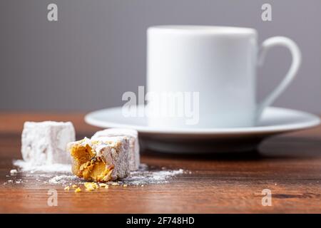 Traditioneller türkischer Kaffee in klassischen Tassen mit türkischen Köstlichkeiten. Im Hintergrund befindet sich eine Kaffeekocher aus Metall. Stockfoto