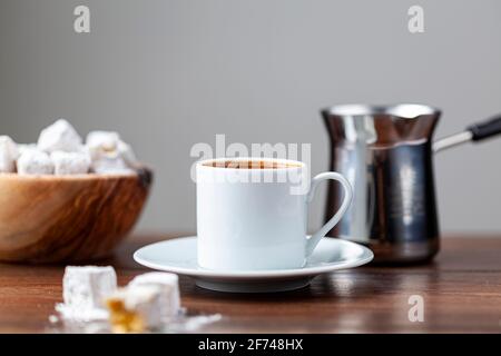 Traditioneller türkischer Kaffee in klassischen Tassen mit türkischen Köstlichkeiten. Im Hintergrund befindet sich eine Kaffeekocher aus Metall. Stockfoto