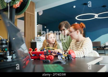 Portrait von zwei Kindern, die während der Ingenieursklasse in der Schule Roboter bauen, mit weiblicher Lehrerin, die hilft, Raum kopieren Stockfoto