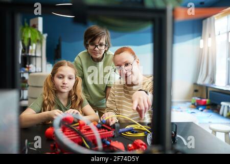 Vorderansicht Porträt einer Lehrerin, die während des Engineering- und Robotikunterrichtete an der modernen Schule auf den 3D-Drucker zeigt, Kopierraum Stockfoto