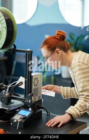 Vertikale Seitenansicht Porträt von jungen rothaarigen Frau mit 3D-Drucker in der Ingenieurklasse Stockfoto