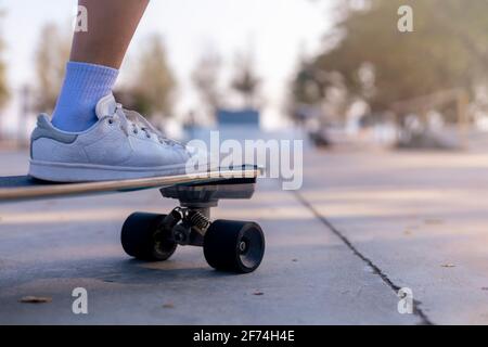 Nahaufnahmen asiatischer Frauen surfen Skate oder Skateboard im Freien am schönen Morgen. Glückliche junge Frauen spielen am Morgen im Rampenpark Surfskaten. Nahaufnahme Stockfoto