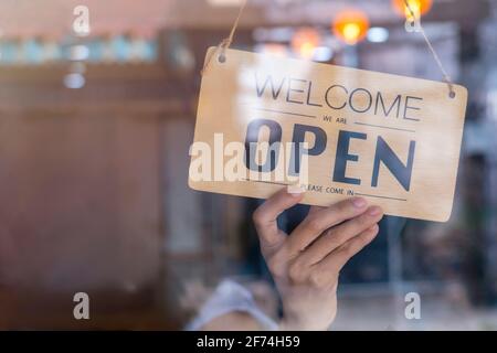 Hand des asiatischen Besitzers Einzelhandel, Café Frau drehen Schild zu öffnen. Schutz vor einer Pandemie des Coronavirus. Geöffnet Geschäft, Restaurant oder Pub wegen l Stockfoto