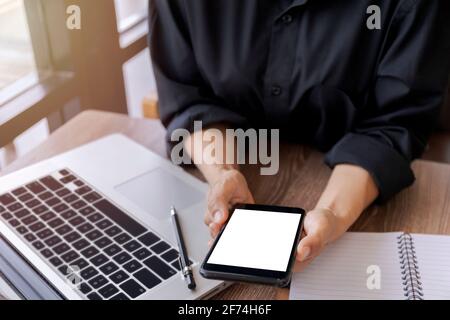Weibliche Hände halten Smartphone mit leerem weißen Bildschirm. Frauen Hände Arbeitsplatz, Nahaufnahme Hand hält Smartphone leeren Bildschirm für Text und Inhalt bei Stockfoto