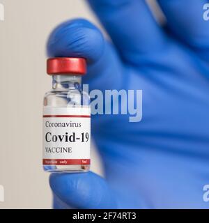 Ärzte Hand in latexblauen Handschuhen hält Covid-19 Coronavirus-Impfstoff Fläschchen. Stockfoto