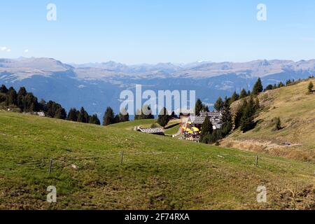 Blick auf die alpine Landschaft. Wiesen, Hügel und Berge. Zaun und Gebäude auf dieser Seite, hohe Berge im Hintergrund. Stockfoto