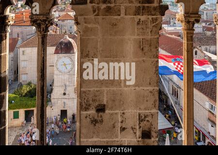 Blick vom Turm durch das mittelalterliche Fenster nach Trogir Altstadtplatz und Uhrenturm Stockfoto