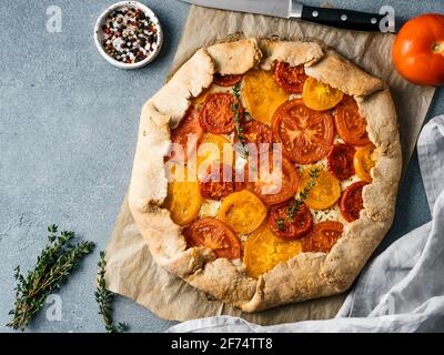 Herzhafte Frische hausgemachte Tomatentarte oder Galette. Ideen und Rezepte für gesundes Mittagessen, appetiezer - ganze Weizen oder Roggen - Weizen Torte mit Tomaten, Parmesan, Mozzarella. Ernte Tomaten. Top View oder flach Stockfoto