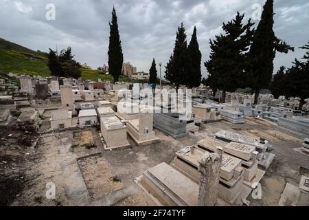 tzfat-israel. 22-03-2021. Überfüllte Gräber, auf dem neuen Friedhof in der Stadt tzfat, im Hintergrund eines bewölkten Winterhimmels Stockfoto