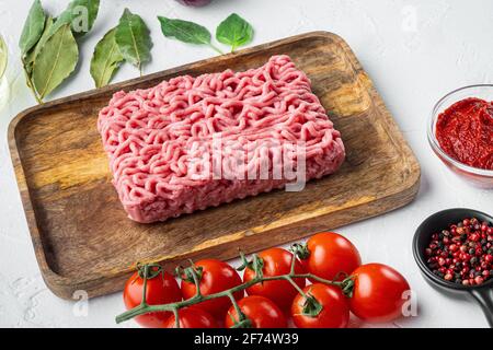 Zutaten für Bolognese-Sauce, Hackfleisch, Tomaten, Kräuter-Set, auf Holzplatte, Auf weißem Stein Hintergrund Stockfoto