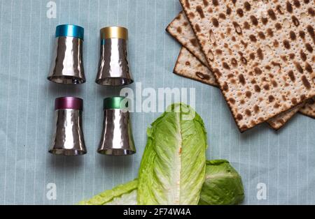 Nahaufnahme von Matzah, Salatblättern und vier Tassen Silber auf hellem Hintergrund Stockfoto