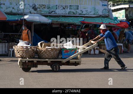 Ein Mann schiebt einen Holzwagen mit Körben in einem Marktgebiet, Cebu City, Philippinen Stockfoto