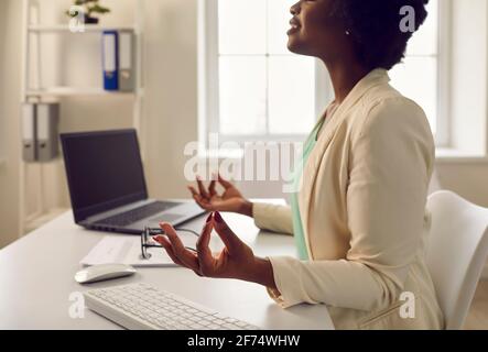 afroamerikanische Angestellte meditieren ruhig am Schreibtisch Hochformat Stockfoto