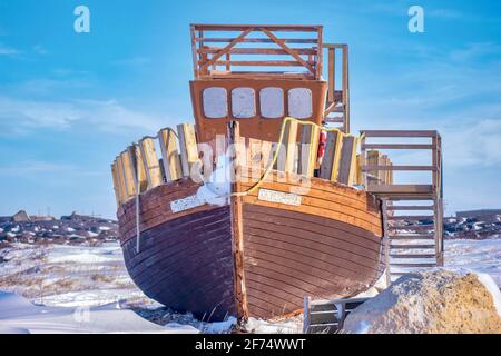 Ein altes Holzboot, das aus dem Wasser und im Schnee in einem öffentlichen Park in Churchill, Manitoba, Kanada, ausgestellt ist. Stockfoto