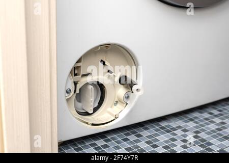 Der Filter der Waschmaschine ist verstopft. Filterdeckel der Waschmaschine öffnen. Problem mit dem Wäschewaschen. Stockfoto