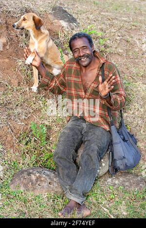 Einheimische Männer warten mit seinem Hund auf einen Bus von Port Mathurin zu den Bergen der Insel Rodrigues, Mauritius Stockfoto