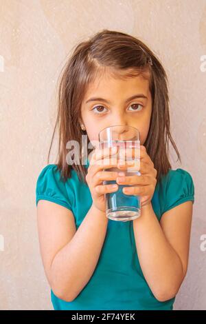 Das Kind hält ein Glas Wasser in den Händen. Selektiver Fokus.Natur Stockfoto