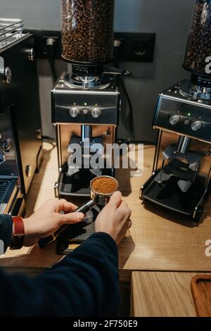 Von oben kann der Barista beim Zubereiten nicht mehr erkennen, dass er eine Kaffeemühle verwendet Aromatischer, frischer Kaffee im Café am Tag Stockfoto