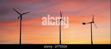 Silhouetten von Windenergieanlagen bei Sonnenuntergang Stockfoto