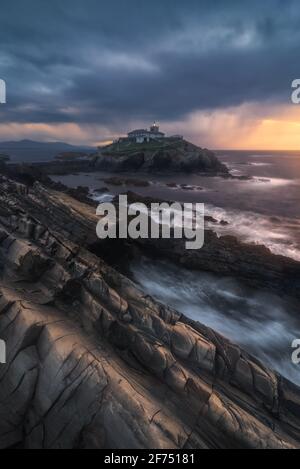 Atemberaubende Landschaft der felsigen Insel mit Leuchtturm im Ozean In der Nähe der felsigen Küste in Faro Tapia de Casariego in Asturien In Spanien unter bewölktem sk Stockfoto