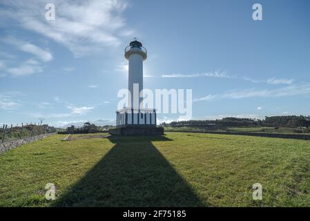 Schatten, der zum weißen Leuchtturm in Faro de Lastres führt In Asturien in Spanien unter wolkenlosem blauen Himmel am Tag Stockfoto