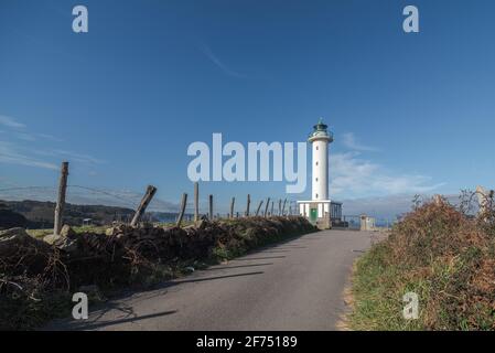 Asphaltstraße, die zum weißen Leuchtturm führt, der in Faro de liegt Lastres in Asturien in Spanien unter wolkenlosem blauen Himmel in Tagsüber Stockfoto