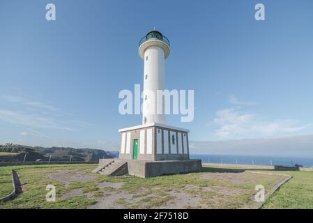 Asphaltstraße, die zum weißen Leuchtturm führt, der in Faro de liegt Lastres in Asturien in Spanien unter wolkenlosem blauen Himmel in Tagsüber Stockfoto