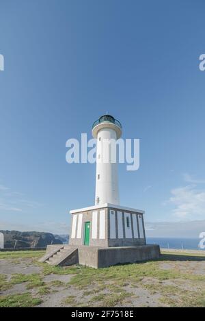 Asphaltstraße, die zum weißen Leuchtturm führt, der in Faro de liegt Lastres in Asturien in Spanien unter wolkenlosem blauen Himmel in Tagsüber Stockfoto