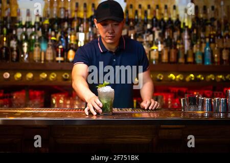 Der junge asiatische Barkeeper gibt Ihnen einen Grapefruitsaft-Gin-Cocktail In der Bar, nachdem er fertig war, um es vorzubereiten Stockfoto