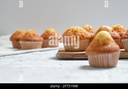 Leckere hausgemachte frisch gebackene süße Muffins in Pappbechern arrangiert Auf dem Tisch Stockfoto