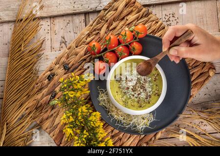 Blick von oben auf den anonymen Koch mit einer Schüssel lecker Vegetarische Sahnesuppe mit zerdrückten Pistazien und Gewürzen darauf Stockfoto
