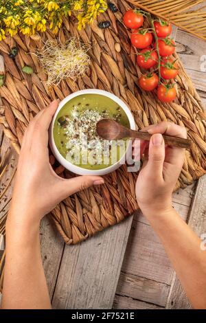Draufsicht auf Ernte unkenntlich kochen mit Holzlöffel und Schüssel mit appetitanregenden Sahnesuppen mit zerdrückten Pistazien und Gewürzen Stockfoto