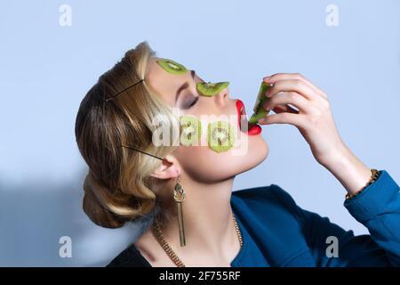 Modefoto einer Frau, die mit Kiwi-Scheiben posiert Ihr Gesicht Stockfoto