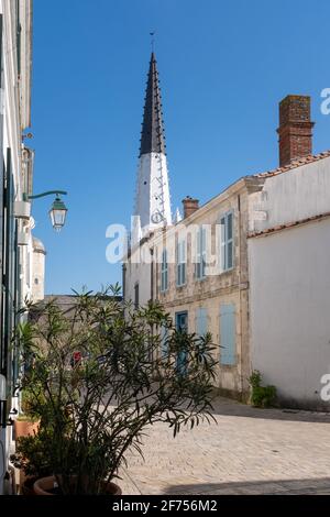 Blick auf eine leere Straße und den Kirchturm von Ars-en-Ré, aufgenommen auf der Isle of Rhé an einem sonnigen späten Wintertag Stockfoto