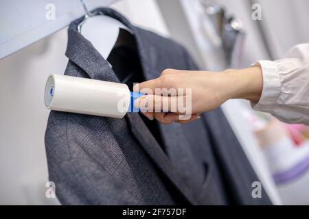 Womans Hand mit Flusenrolle bewegt sich entlang Blazer. Stockfoto