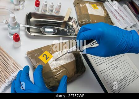 Spezialisierte Polizei öffnen Drogenbündel im Kriminallabor, konzeptuelles Image Stockfoto