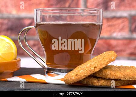 Haferflockenkekse, begleitet von einer Tasse Tee und in Scheiben geschnitten Zitrone Stockfoto