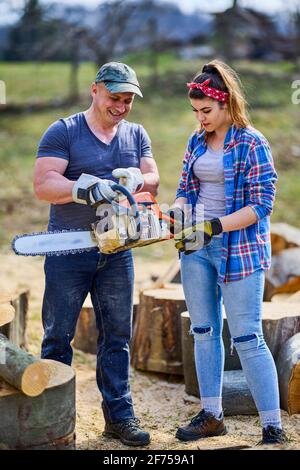Holzfäller lehrt seinen Lehrling, wie man die Kettensäge verwendet Stockfoto