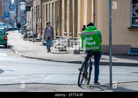 Riga, Lettland - 30. September 2020:Lebensmittellieferer der Firma Wolt auf dem Fahrrad in der Stadt Riga. Wolt ist ein finnisches Technologieunternehmen, das für seine bekannt ist Stockfoto