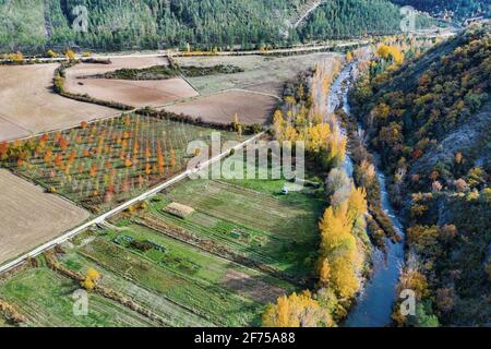 Luftaufnahme eines Flusses und Ackerland mit Ufervegetation im Herbst. Stockfoto