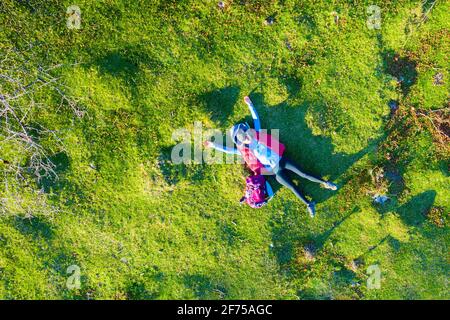 Luftaufnahme einer jungen Wanderin, die auf dem Rücken auf einer Wiese liegt. Stockfoto