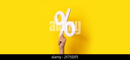 Hand hält Prozentzeichen über gelbem Hintergrund Stockfoto