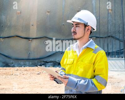 Junge schöne asiatische Tunnel Engineering trägt hohe Sichtbarkeit Jacke und Weißer Schutzhelm, der am Tunnel arbeitet und mit einem digitalen Tablet arbeitet Konstruktion Stockfoto