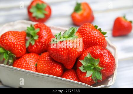 Nahaufnahme von isolierten reifen frischen Erdbeeren vom deutschen Bauernmarkt In Pappkarton auf weißem Holztisch Stockfoto