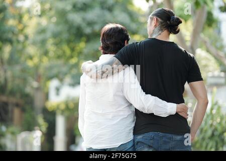 Ältere Frau und ihr erwachsener Sohn umarmen sich beim Gehen im Freien Gemeinsam und über Neuigkeiten diskutieren Stockfoto