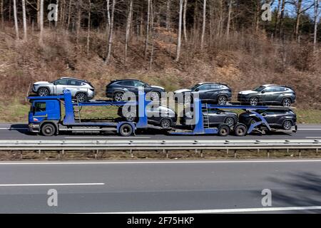 RIMO-KFZ-LKW Scania, der auf der Autobahn mit neuen Autos beladen ist. Stockfoto