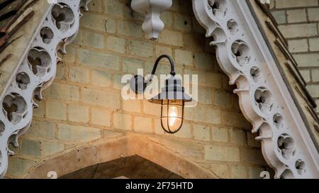 Detail einer schwarzen Metalllampe mit einer ligthed bulb Hängt an einer gelben Ziegelwand Stockfoto